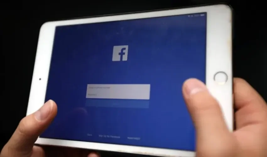 Una persona sostiene un dispositivo electrónico en la que aparece la página de inicio de la red social Facebook. EFE/ Luong Thai Linh